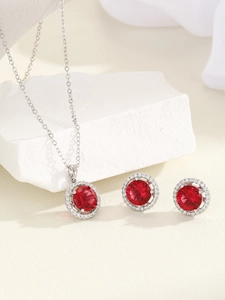 Macro shot of silver jewelry set featuring red zircon necklace and matching stud earrings