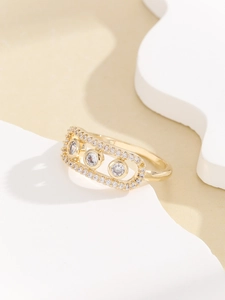 Detail showing gold ring with three moving clear zircons in a micro-paved oval frame