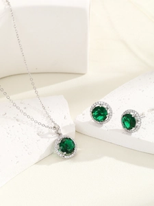 Macro shot of sparkling emerald green halo jewelry set with necklace and earrings on stone