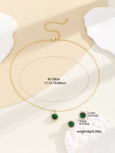 Detail view of gold necklace and emerald green earrings set with sparkling zircons