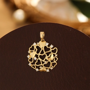 Détail macro du pendentif cœur évidé doré orné de cristaux sur support sombre