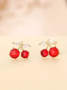Macro shot of red cherry stud earrings with gold metal and sparkling leaf accents