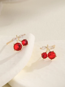 Close-up of elegant cherry earrings with red crystals and gold-plated leaf details