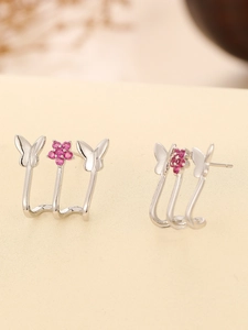Dettaglio di orecchini a lobo triplo effetto con fiori in zircone rosa e farfalle