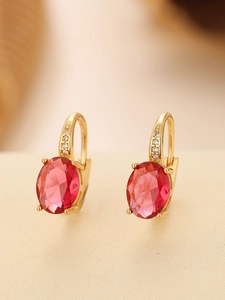 Macro detail of gold oval ruby earrings with cubic zirconia pavé and claw setting