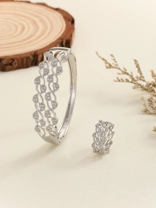 Detailed close-up of silver-tone hollowed wave pattern bangle and ring jewelry set with zircons