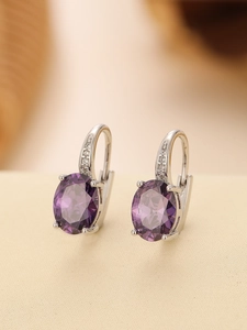 Detailed macro shot of vintage oval purple crystal earrings with silver diamond inlay