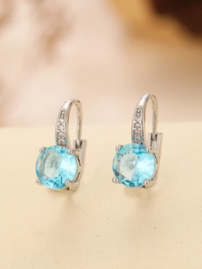 Detailed view of silver stud earrings with large round blue gems and zircon accents