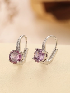 Macro shot of silver huggie earrings with round purple stones and pavé cubic zirconia