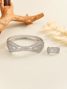 Macro view of silver bow jewelry set with zircon pavé on a textured background