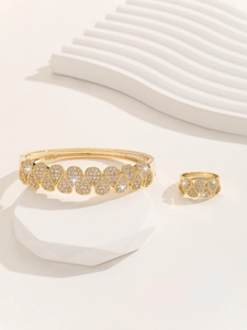 Detail of gold jewelry set with intricate micro-pave white zircons and leaf patterns