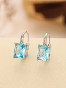 Macro view of silver earrings with large rectangular blue gemstone and sparkling zirconias