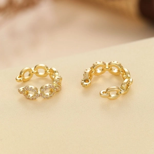 Golden chain cuff earrings with micro-set zircons on textured minimalist background
