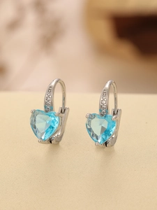 Detail of silver hoop earrings with heart-shaped light blue gemstone and small zircons