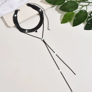 Macro shot of black rhinestone choker set on marble background with Y-shaped tassel detail