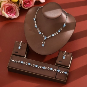 Detailed view of leaf-shaped silver necklace and earrings set with blue pear-cut zircons