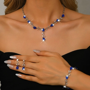 Silver jewelry set featuring blue pear-cut gems on model with vine-style necklace