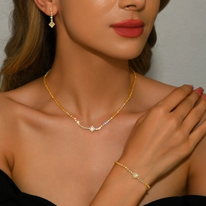 Elegant gold jewelry set with necklace, bracelet and earrings featuring diamond rhombus charms
