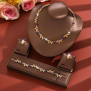 Close-up of golden vine necklace and blue flower jewelry set on leather display