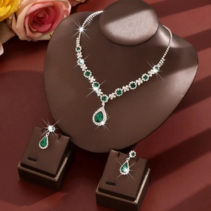 Macro detail of bridal jewelry set with pear-cut emerald gemstones and silver zircon inlay