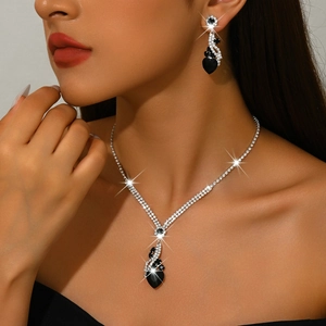 Close-up of black heart pendant necklace and earrings set with sparkling rhinestones