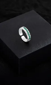Makro-Detail des versilberten geflochtenen Rings mit smaragdgrünen Zirkonia-Steinen