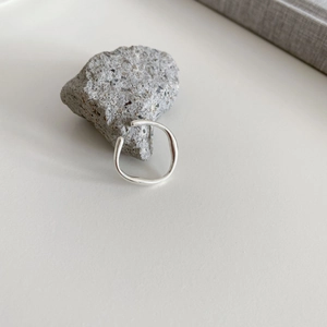 Nahaufnahme eines unregelmäßigen silbernen Wellenrings auf grauem Naturstein