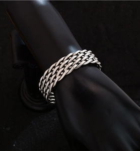 Close-up of retro silver-tone wide braided metal cuff bracelet with detailed texture