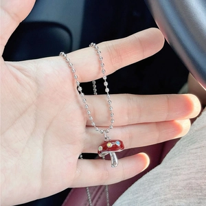 Détail du pendentif champignon en émail rouge sur un collier à billes argenté