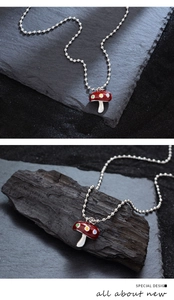 Vue détaillée du pendentif champignon en émail rouge avec pois et chaîne à billes