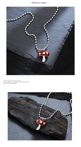 Vue détaillée du pendentif champignon en émail rouge avec pois colorés et chaîne à billes