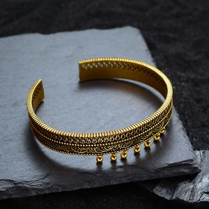 Ethno-Armreif in Antikgold mit floralem Durchbruchmuster und kleinen Metallglocken