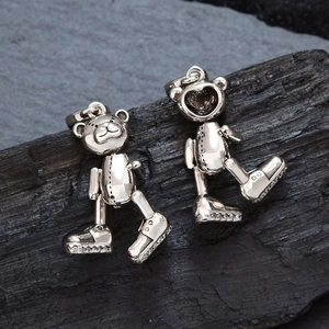 Colgantes de osito articulados en plata vintage con zapatos de diamantes sobre piedra oscura