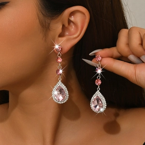 Dettaglio degli orecchini a goccia rosa con micro-pave di zirconi indossati dal modello