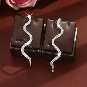 Detailed view of silver snake drop earrings with sparkling white crystals on display