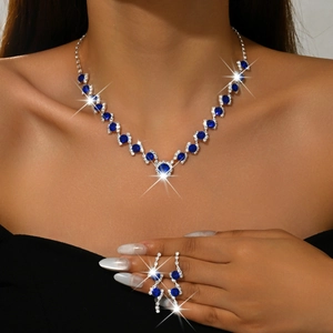 Detailed view of luxury V-shaped blue gemstone necklace and drop earrings on model
