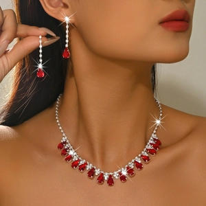 Close-up of bridal necklace set featuring teardrop red gems and sparkling crystals