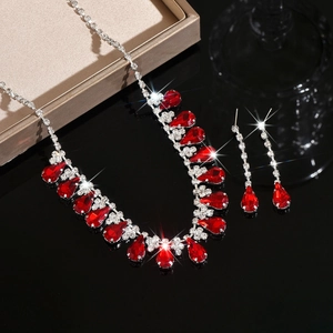Detail view of shimmering water drop tassel necklace and earrings with red gemstones