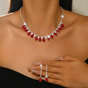Close-up of sparkling bridal jewelry set with red teardrop pendants and silver tassels