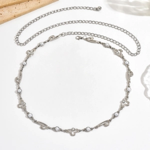 Cadena de cuerpo plateada con perlas blancas y flores caladas sobre fondo blanco puro