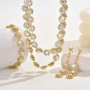 Detailed view of luxury gold flower jewelry set with sparkling crystals on white pedestals