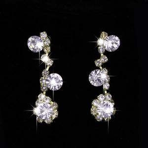 Detailed close-up of sparkling crystal drop earrings with golden metal base on black background