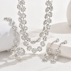 Macro shot of silver sunflower jewelry set featuring necklace and earrings on white pedestals