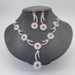 Detail of silver claw chain jewelry set with white rhinestones and red floral accents