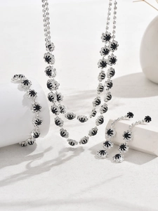 Detail of silver alloy jewelry set with black round crystals on white display blocks