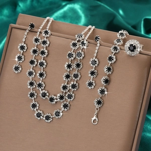 Macro shot of silver sunflower jewelry set with black gemstones on green satin
