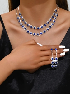 Close-up of double-layer sunflower necklace and drop earrings set with blue gems