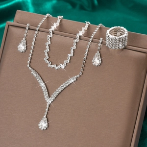 Détail d'une parure de bijoux de mariée en strass argentés sur fond de soie verte