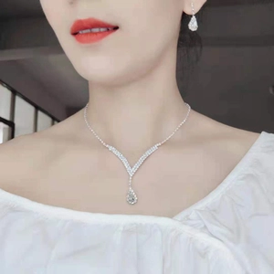 Gros plan d'un collier en V et de boucles d'oreilles en cristal sur un modèle de mariée