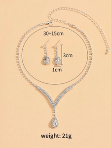 Détail du parure de bijoux de mariée argentée avec collier en V et boucles d'oreilles